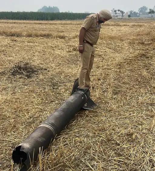 अमृतसर में खेत में पड़े रॉकेट को चेक करते पंजाब पुलिस के अधिकारी।